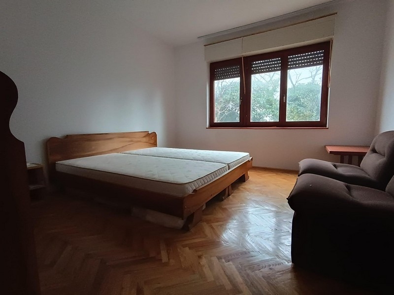 Spálňa s manželskou posteľou a oknom v apartmánovom dome na predaj v Crikvenici, Chorvátsko