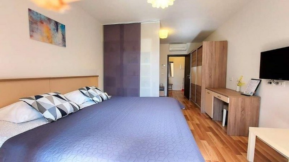Spálňa v jednom z troch apartmánov domu na predaj na Istrii s veľkou posteľou, skriňou a TV.
