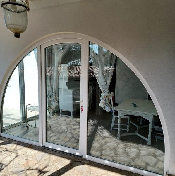 Veľká klenutá presklená predná časť vily na predaj na ostrove Cres v Chorvátsku, s pohľadom na biely interiér a výhľad na more