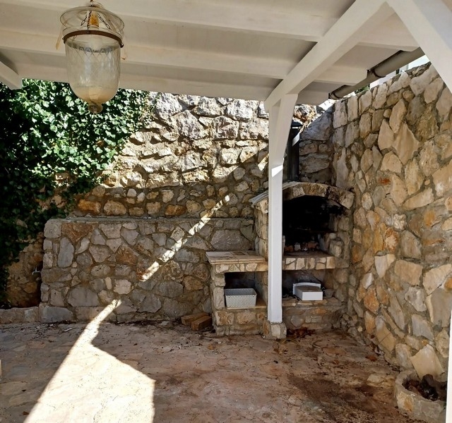 Vonkajšia kuchyňa s tradičnou kamennou pecou vo vile na predaj na ostrove Cres v Chorvátsku pod bielou strechou