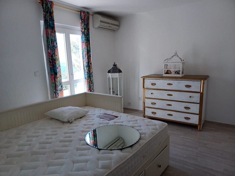 Spálňa s manželskou posteľou a bielou komodou vo vile na predaj na ostrove Cres, Chorvátsko, s výhľadom do prírody