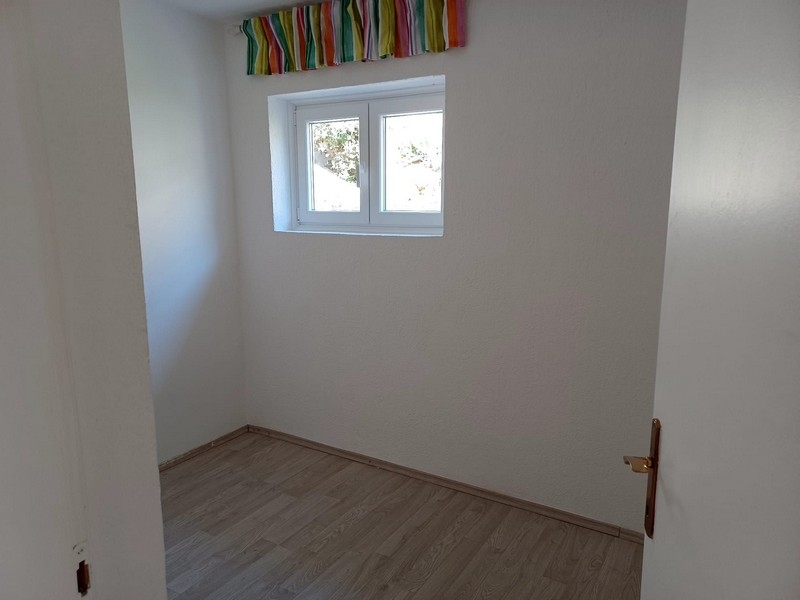 Jednoduchá, prázdna izba s oknom a drevenou podlahou vo vile na predaj na ostrove Cres v Chorvátsku