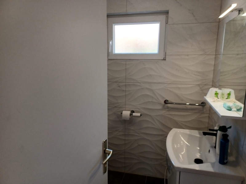 Kúpeľňa s moderným vlnitým obkladom a bielym umývadlom vo vile na predaj na ostrove Cres v Chorvátsku.