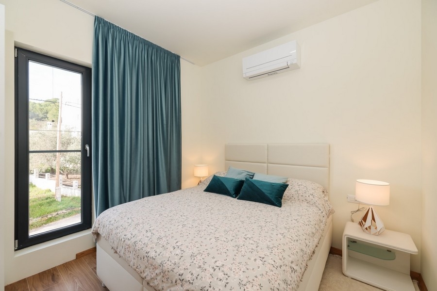 Dvojposteľová izba vo svetlých farbách a výhľadom z okna vo vile na ostrove Ugljan, ponúkaná na predaj.