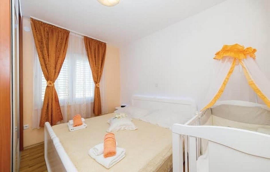 Spálňa s manželskou posteľou a detskou postieľkou v apartmánovom dome v Kaštel Lukšić, Chorvátsko