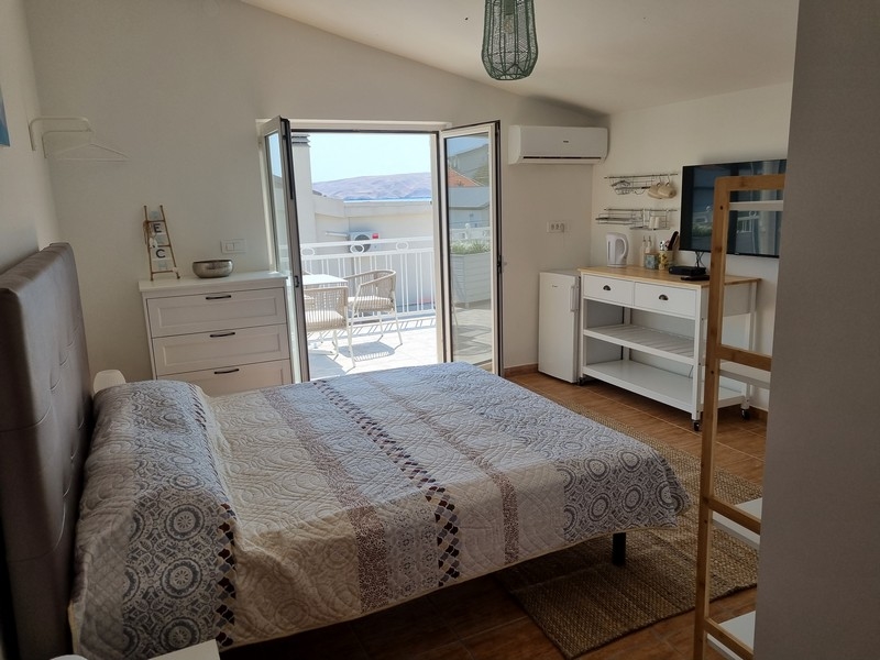 Svetlý štúdiový apartmán s manželskou posteľou, integrovanou kuchyňou, balkónovými dverami s výhľadom na more, na predaj v Karlobagu, Chorvátsko, časť bytového domu priamo pri mori.