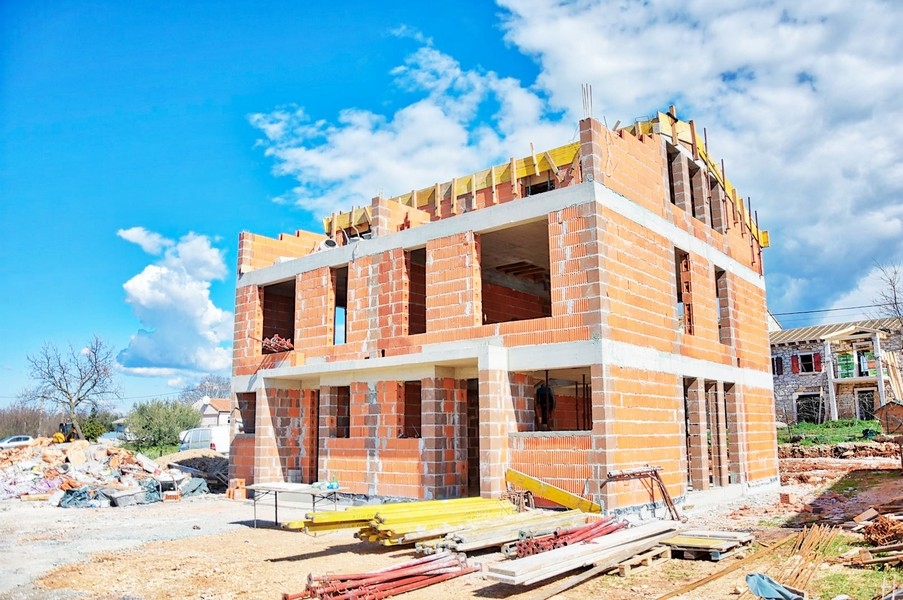 Plášť dvojdomu vo fáze výstavby s tehlami a lešením