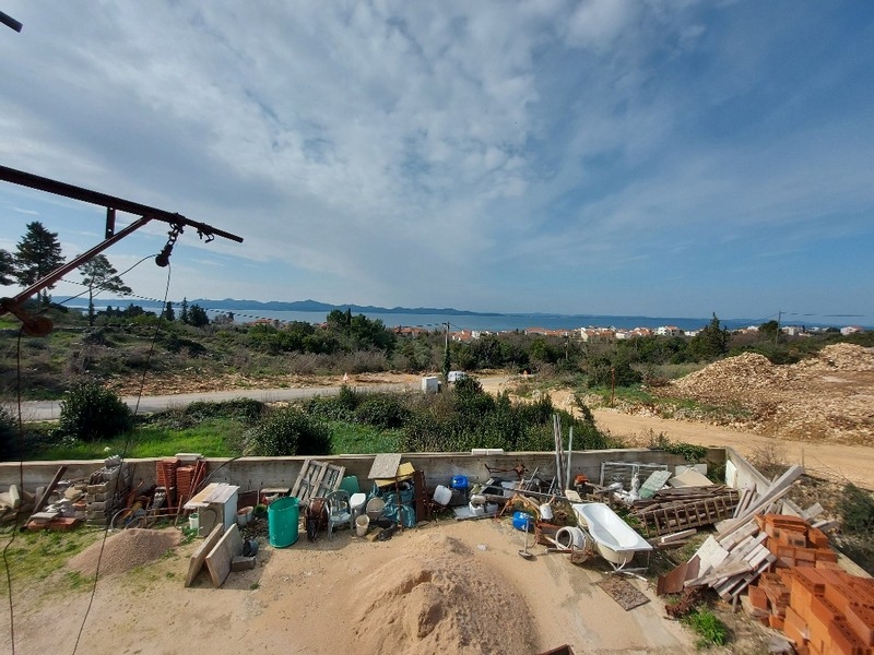 Pohľad zozadu na rozostavaný rodinný dom v Diklo neďaleko Zadaru v Chorvátsku s materiálmi roztrúsenými po okolí