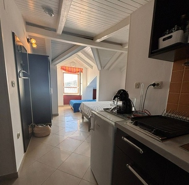 Kompaktná kuchynka s priľahlým priestorom na spanie v chorvátskej nehnuteľnosti. 4 jedálenský stôl s výhľadom na prístav cez okno nehnuteľnosti v Chorvátsku