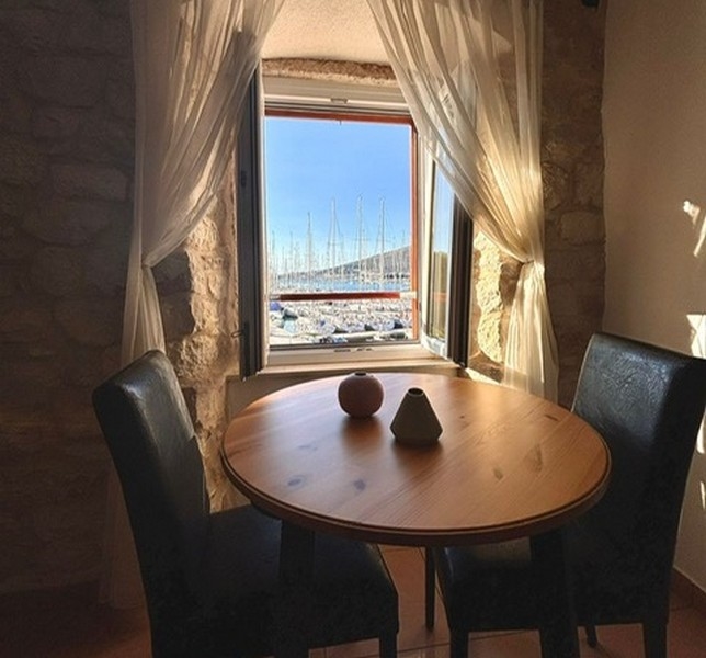 Izba so šikmým stropom a výhľadom na prístav cez okno v nehnuteľnosti v Chorvátsku