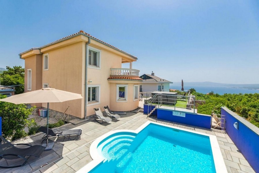 Dvor apartmánového domu v Chorvátsku s bazénom a ležadlami, výhľad na more