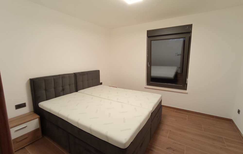 Podobný pohľad na spálňu nehnuteľnosti v Chorvátsku s nočným stolíkom a zatvoreným oknom.