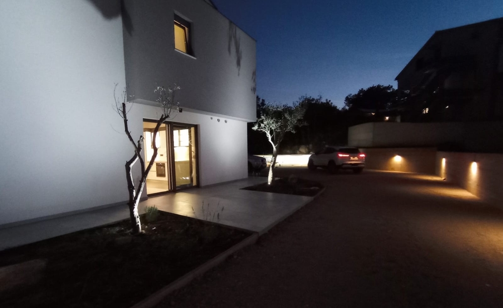 Nočný záber nehnuteľnosti v Chorvátsku s vonkajším osvetlením a autom zaparkovaným vo dvore.