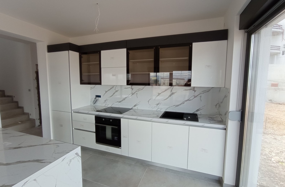 Interiérový pohľad na modernú kuchyňu s bielym nábytkom v nehnuteľnosti v Chorvátsku.