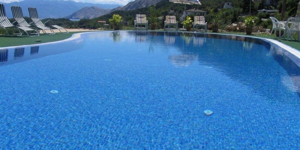 Modrý bazén s výhľadom na hory obklopený ležadlami, chorvátska nehnuteľnosť