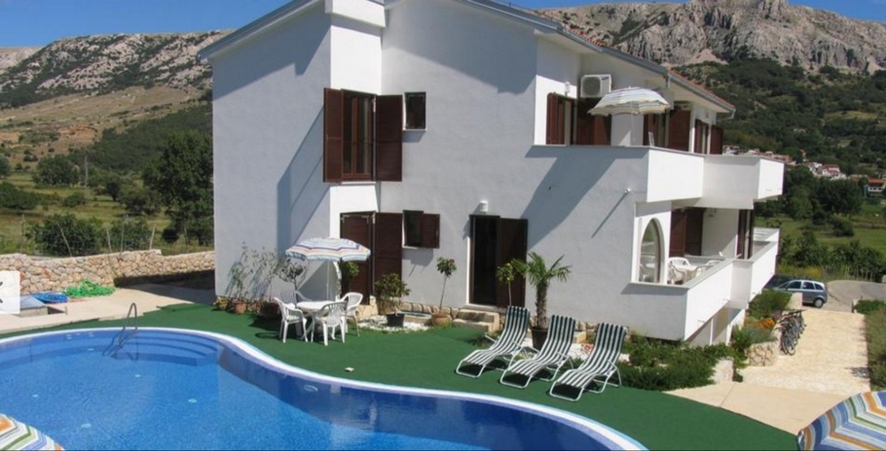 Letný dom v Chorvátsku s modrým bazénom a ležadlami pred hornatou krajinou, chorvátska nehnuteľnosť