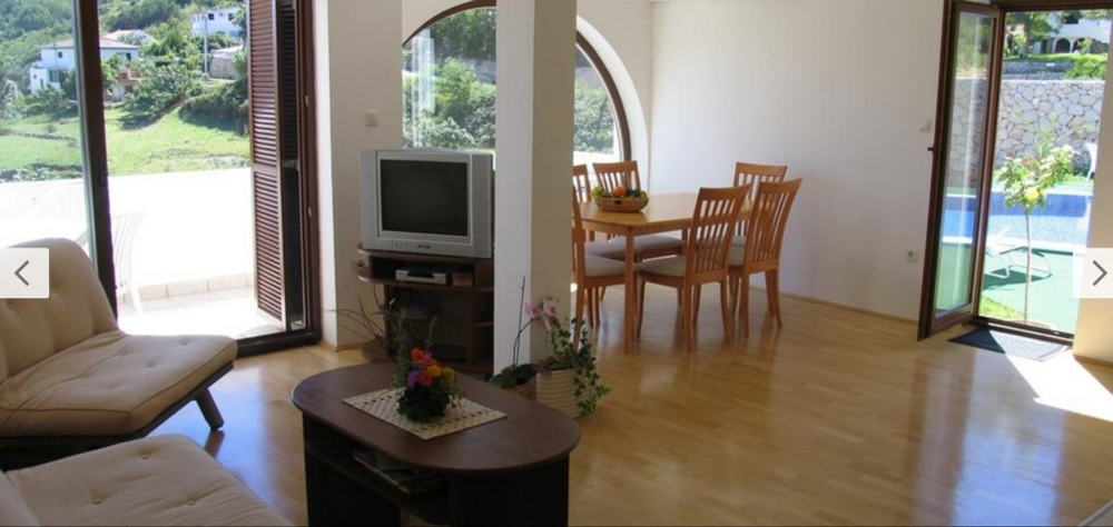 Vnútorný pohľad na svetlú obývačku s drevenými podlahami a prístupom k bazénu, nehnuteľnosť Chorvátsko