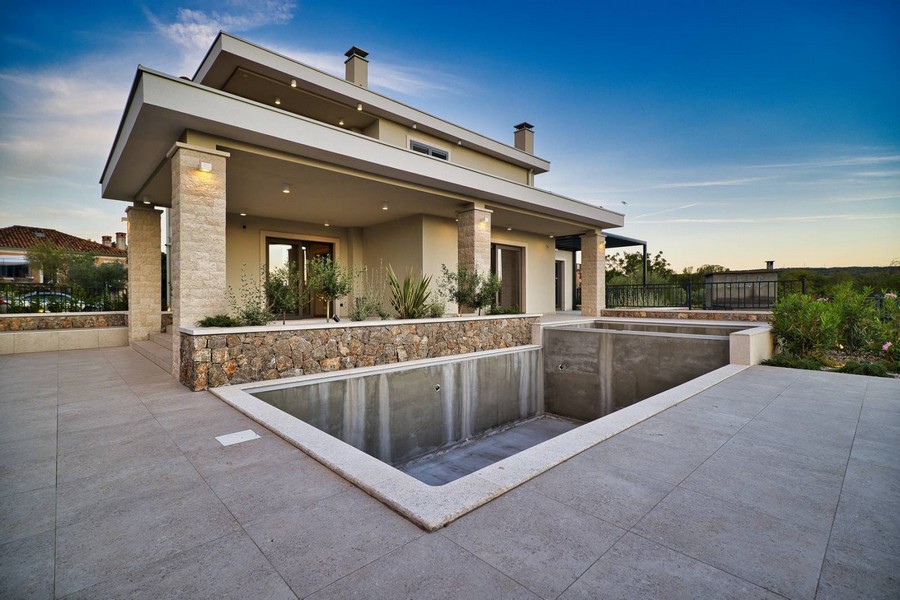 Bočný pohľad na nehnuteľnosť na ostrove Krk s priestrannou terasou a nedokončeným bazénom pri západe slnka