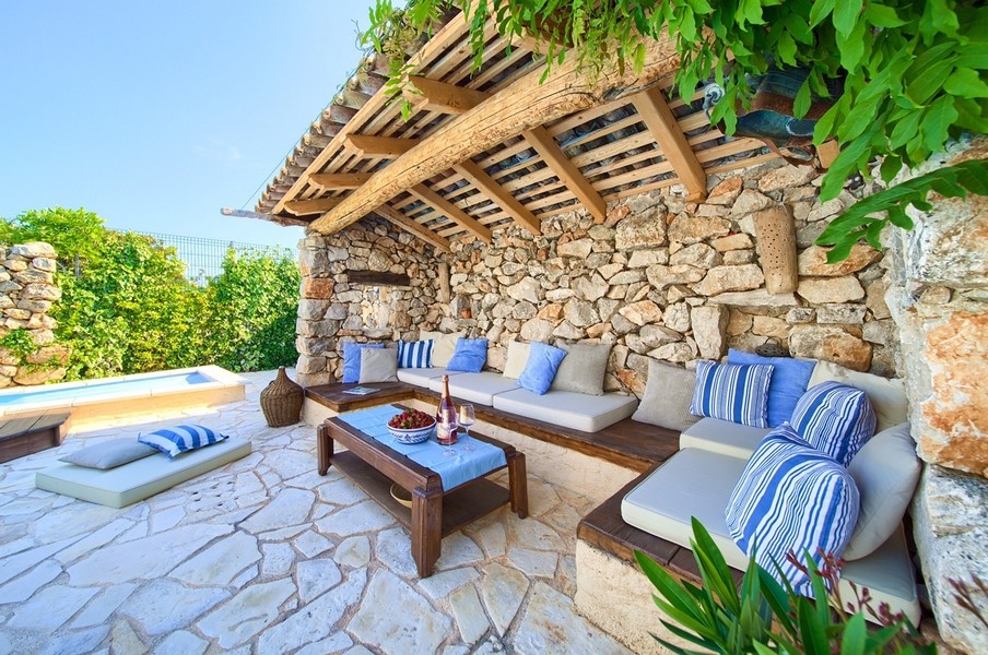 Kryté vonkajšie posedenie s pohodlnými vankúšmi a výhľadom na bazén, typické pre nehnuteľnosť na ostrove Krk.