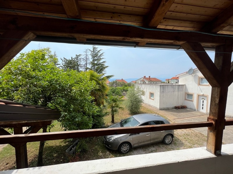 Pohľad z balkóna obklopeného zelenými stromami na obytné budovy v nehnuteľnosti na ostrove Krk.
