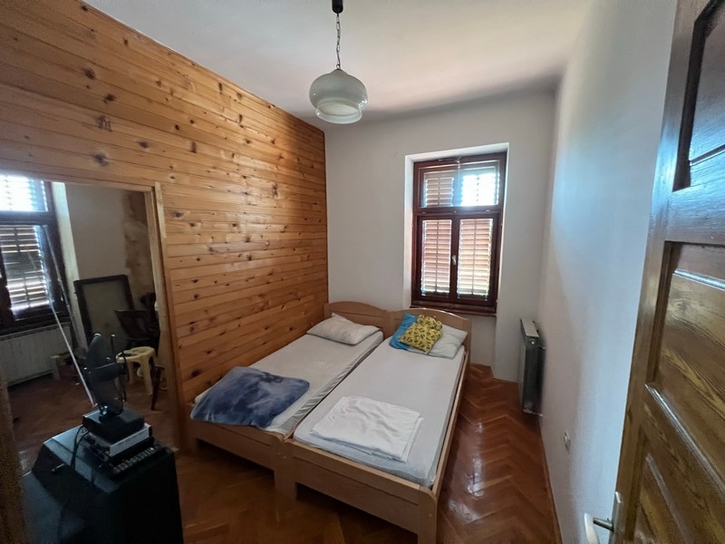 Útulná spálňa s drevenými stenami a dvoma samostatnými lôžkami v nehnuteľnosti na ostrove Krk.