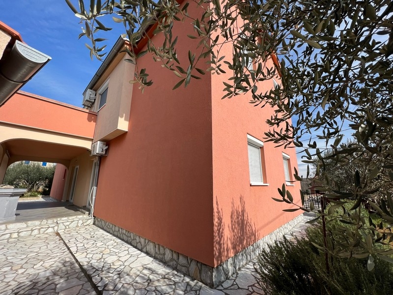 Nehnuteľnosti Chorvátsko, Mesto Krk, Ostrov Krk Kúpa bytového domu, detailný pohľad na bočnú stranu domu s oknami a olivovníkom v popredí