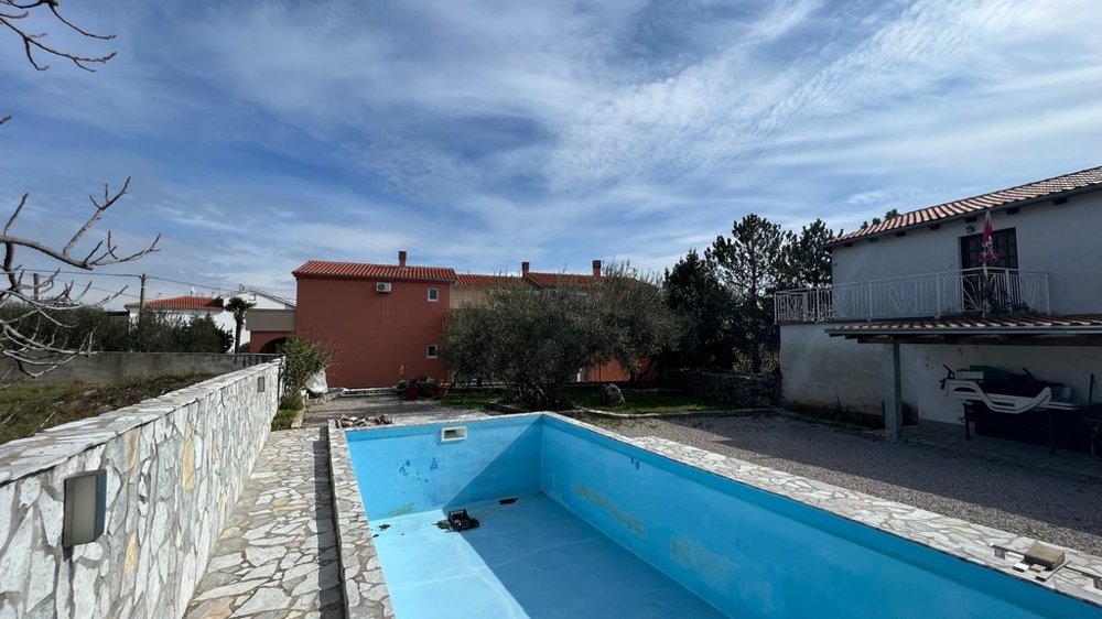 Nehnuteľnosti Chorvátsko, mesto Krk, ostrov Krk Kúpa bytového domu, pohľad zozadu na dom s prázdnym bazénom a záhradou