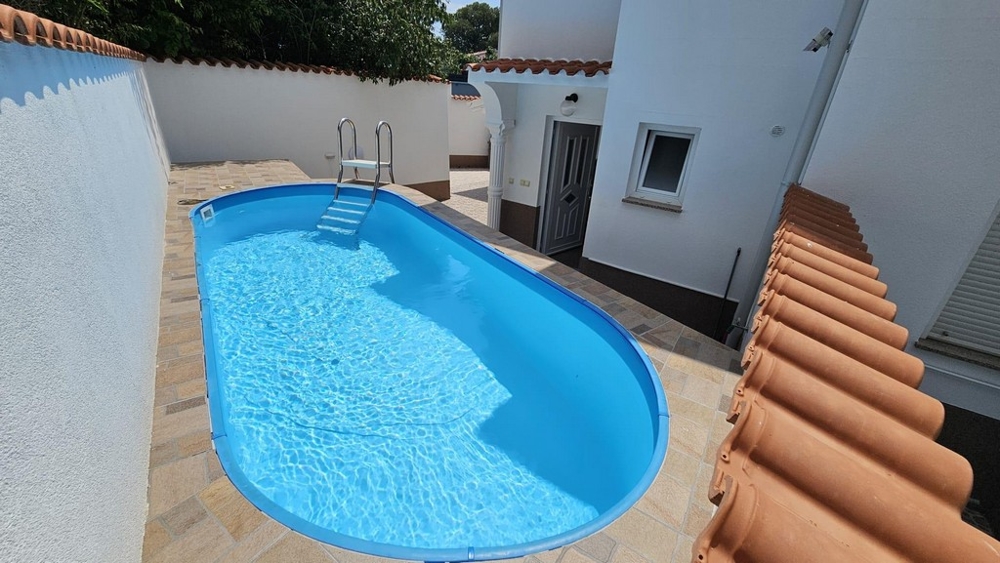 Vonkajší pohľad na žltý dvojdom s balkónmi a schodmi v zelenej záhrade