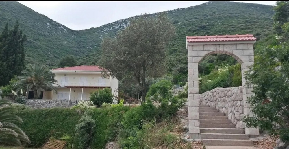 Pohľad z vily na more a vzdialené hory cez otvorené sklenené dvere, polostrov Pelješac