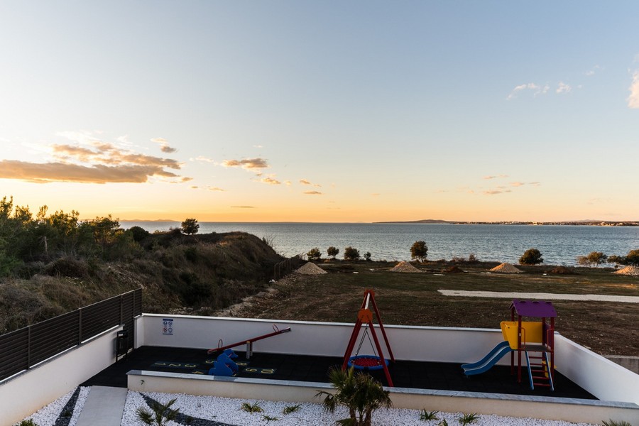 Ohromujúci výhľad na more zo záhrady krásnej chorvátskej nehnuteľnosti s detským ihriskom.