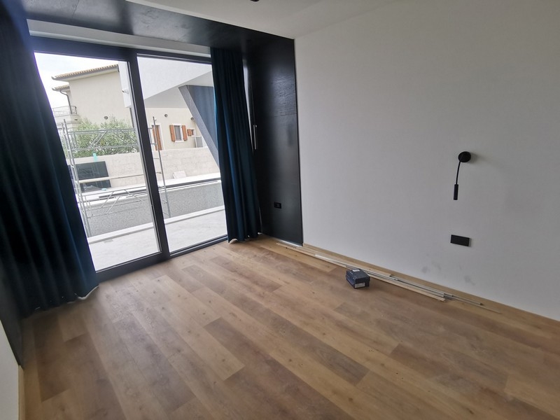 Pohľad do interiéru spálne s drevenými podlahami a veľkým oknom