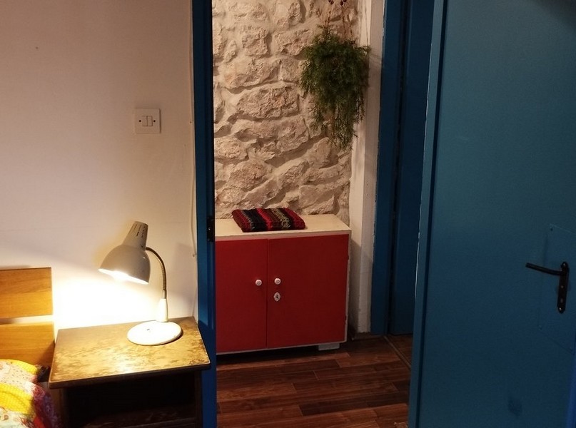 Spálňa s kamennými stenami a rustikálnym šarmom, ideálna na kúpu domu v Chorvátsku.