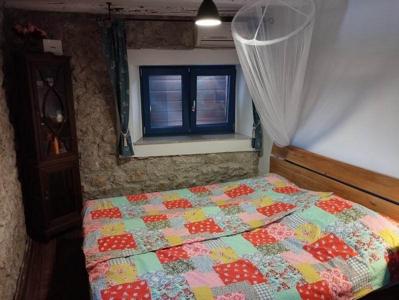 Útulná spálňa s farebným paplónom, ideálna pre každého, kto si chce kúpiť dom v Chorvátsku.