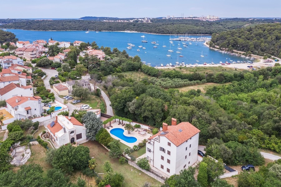 Nehnuteľnosť Chorvátsko, bytový dom na Istrii s výhľadom na more - Panorama Scouting H3025: Letecký pohľad ukazuje malebné pobrežné mestečko s niekoľkými domami a člnmi vo vode