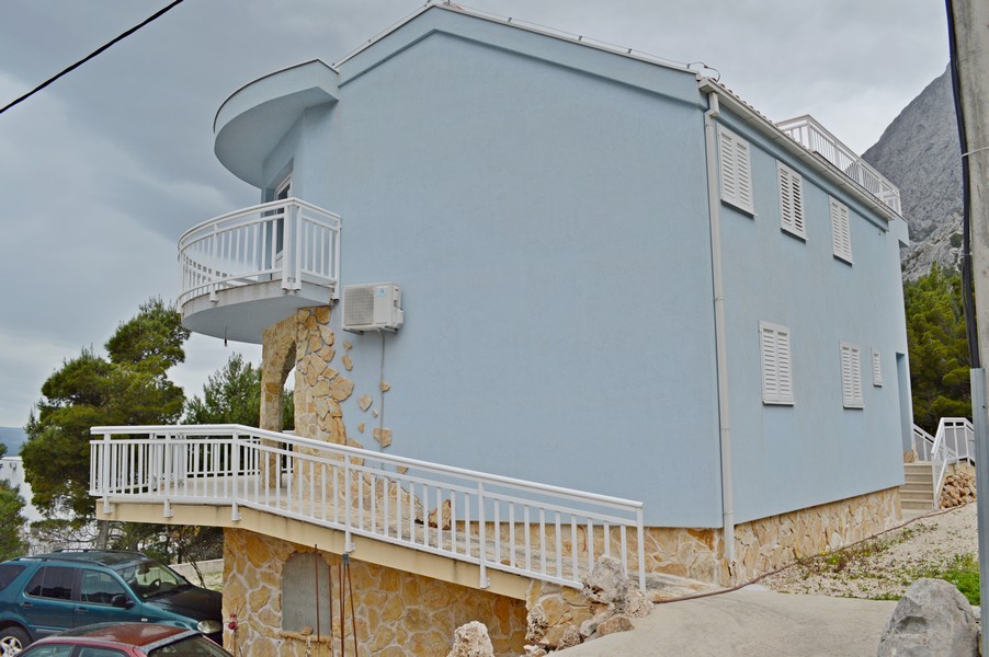 Modrý dom s kamennou stenou a balkónom