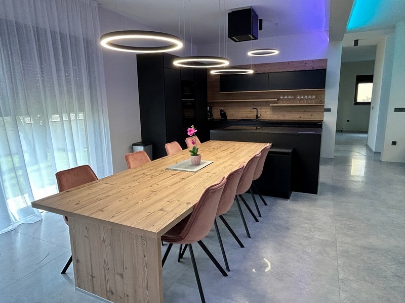 Moderná kuchyňa a jedálenský kút vily so štýlovým osvetlením a dreveným stolom