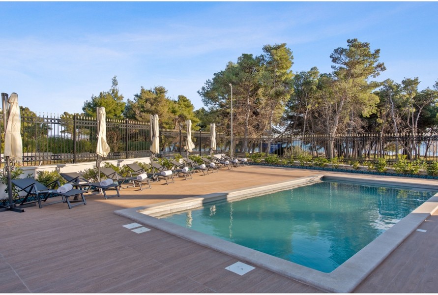 Vonkajší priestor vily H3042 s vyhrievaným vonkajším bazénom a ležadlami obklopený stredomorskými rastlinami