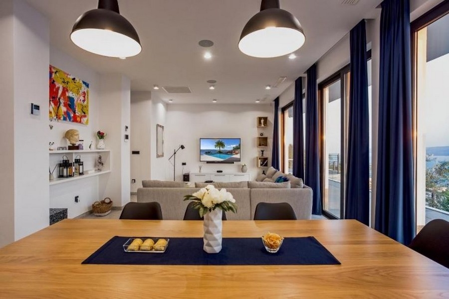 Obývacia izba s veľkou pohovkou, TV s plochou obrazovkou a výhľadom na more cez veľké okná