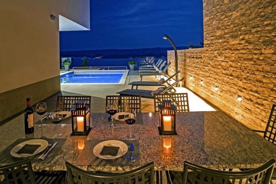 Jedálenský stôl a výhľad na bazén vo večernej atmosfére.