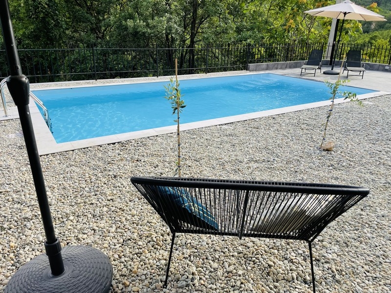 Bazén v záhrade, obklopený kamienkami, s výhľadom na les