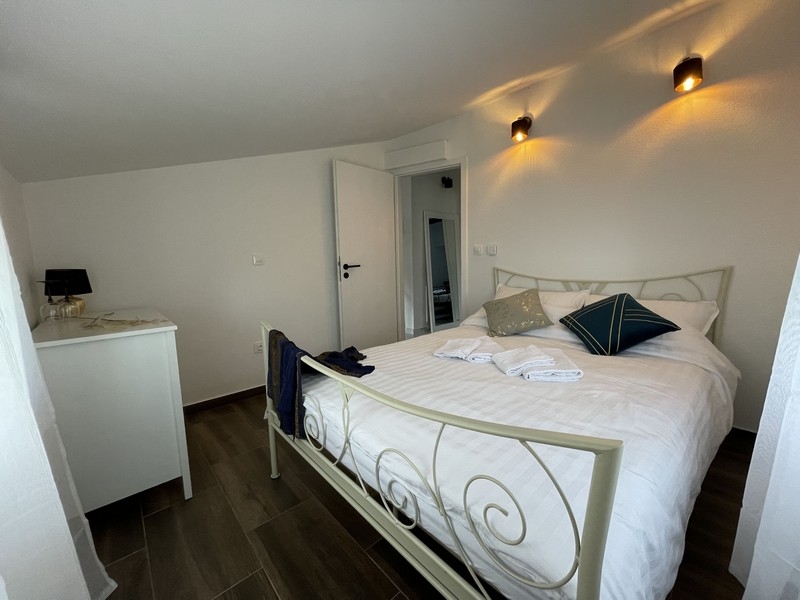 Spálňa s bielou kovanou posteľou, dekoračnými vankúšmi a moderným prostredím