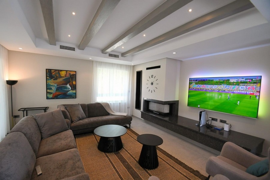 Moderný obývací priestor s veľkou TV a krbom.