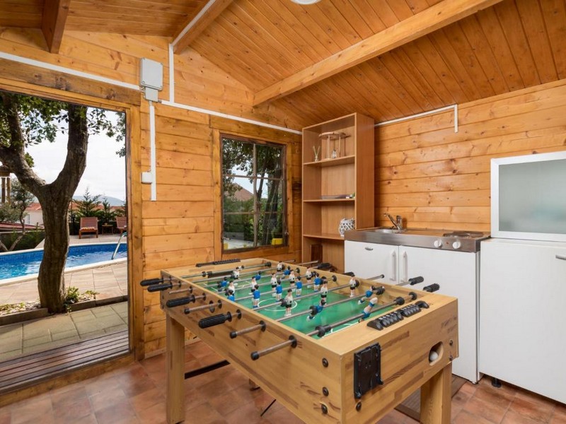 Záhradný domček so stolným futbalom a výhľadom na bazén.