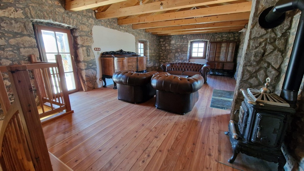 Veľká obývacia izba na poschodí s koženými kreslami a pecou na drevo.