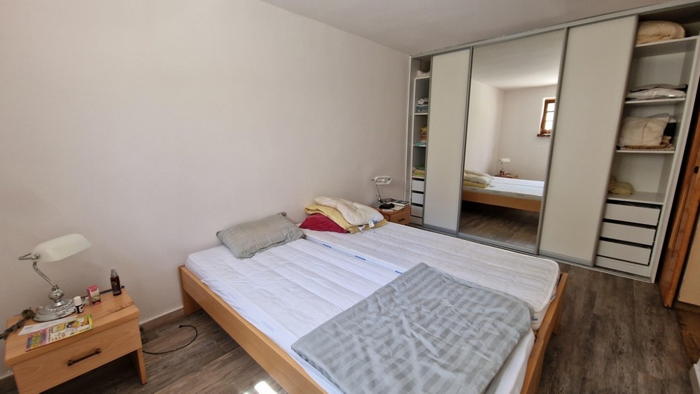 Spálňa s manželskou posteľou, veľkým šatníkom a minimalistickým zariadením.