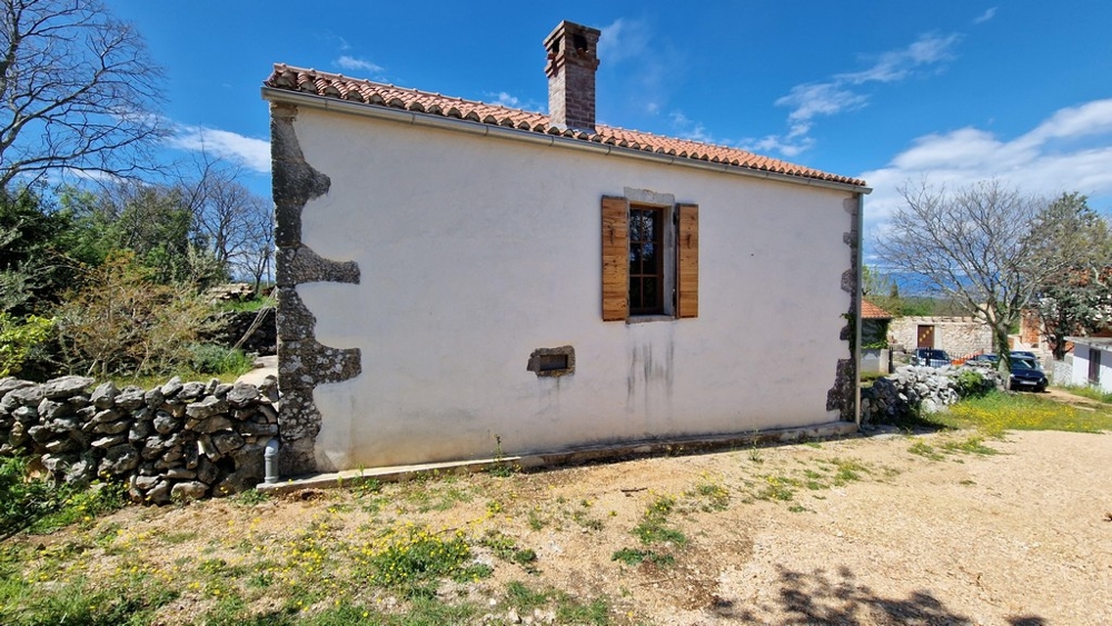 Pohľad na tradičný stredomorský dom s kamennými detailmi a drevenými okenicami.