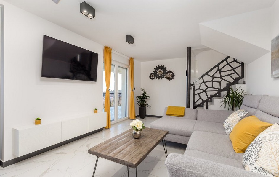 Moderná obývacia izba so sivou pohovkou a žltými prvkami