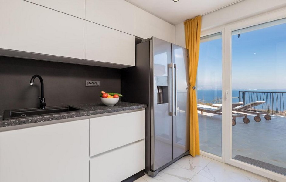 Moderná kuchyňa s výhľadom na more a žltými závesmi