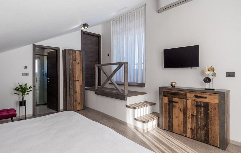 Spálňa s rustikálnym dreveným nábytkom a schodmi