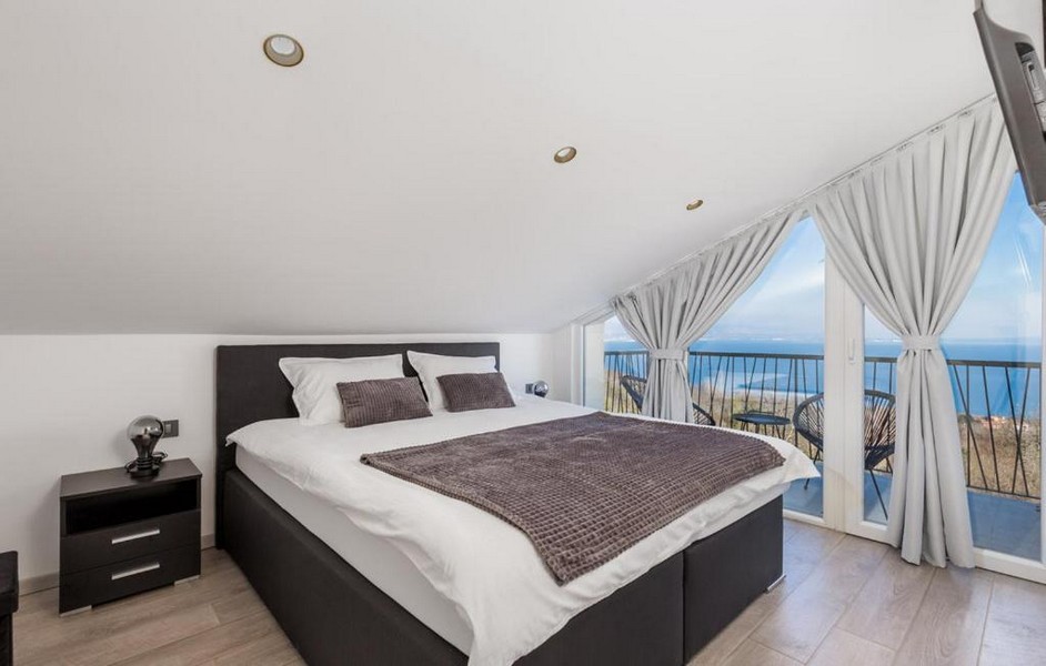 Spálňa so šikmým stropom a výhľadom na more